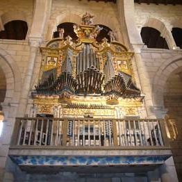 Órgano de tubos de estilo barroco, con rica ornamentación dourada, situado no alto dunha tribuna de madeira.
